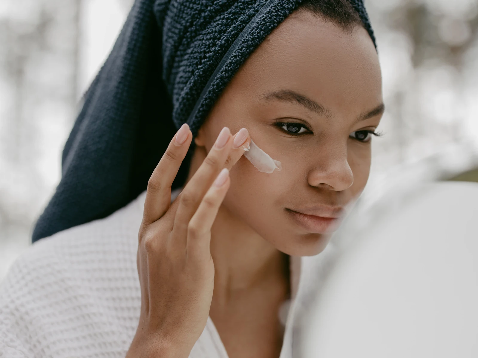 A woman gently applying facial cream at home.