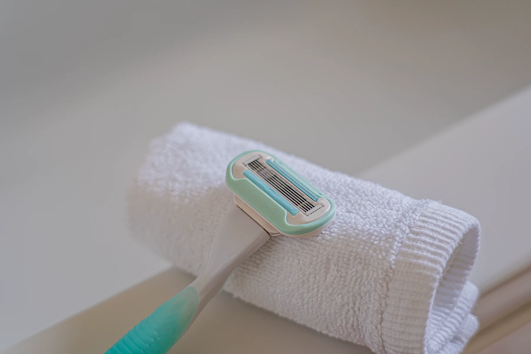 A disposable razor resting on a rolled white towel.